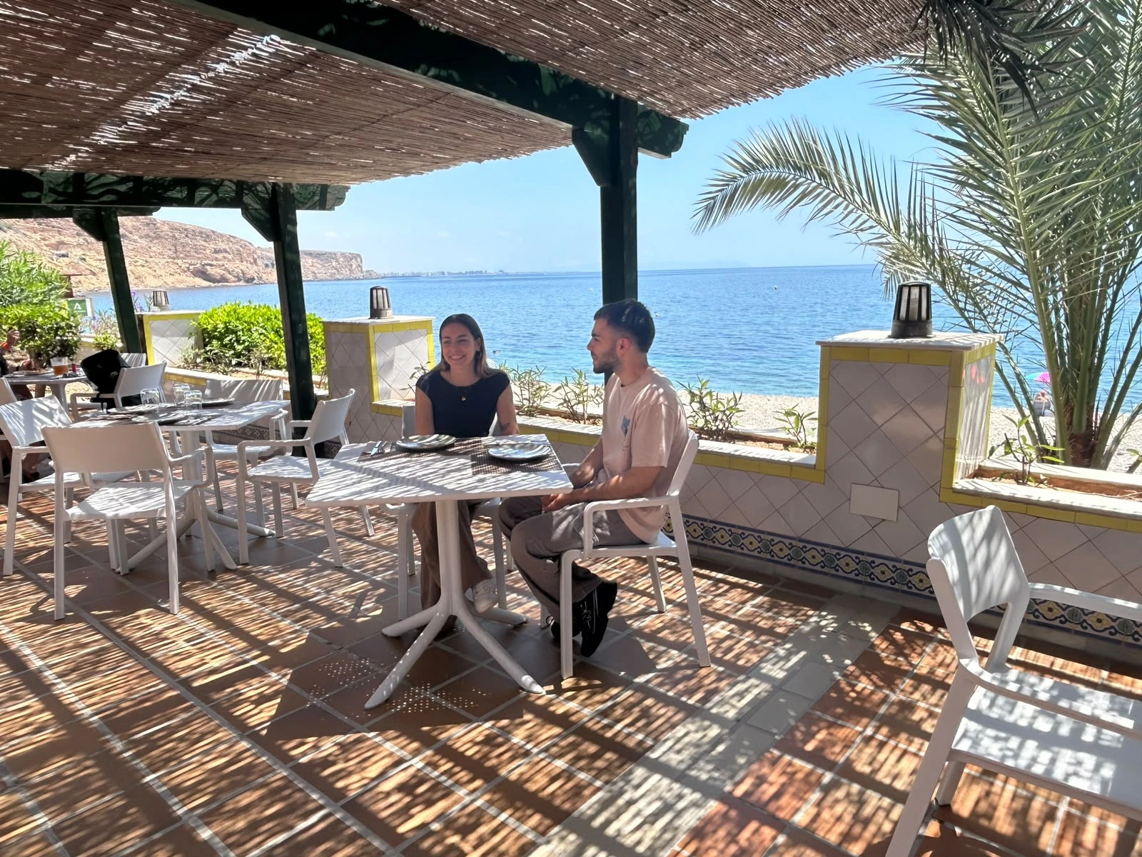 Dos personas disfrutan de una comida con vistas al mar en Aguadulce Pool Club & Restaurant