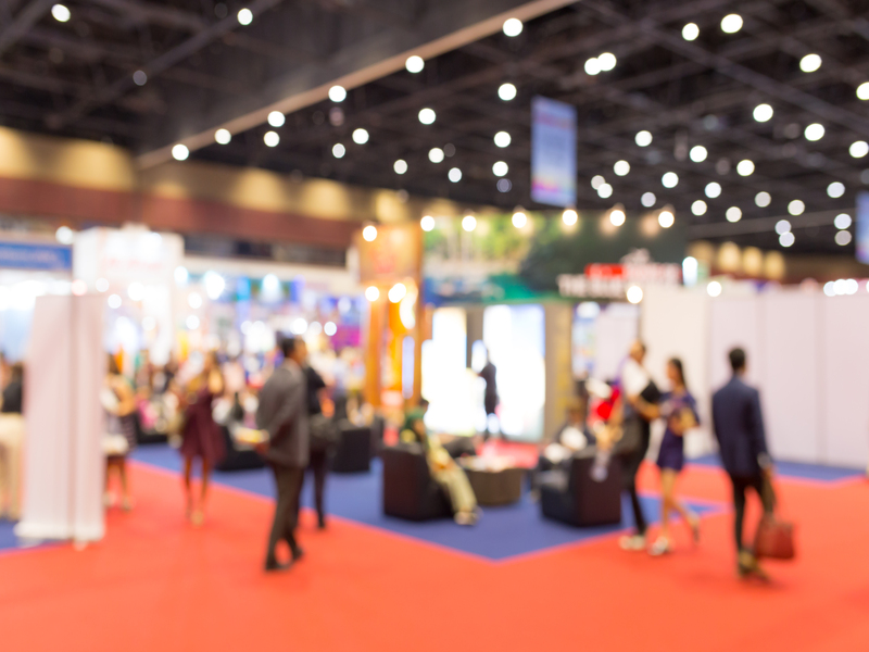Foto pixelada de una feria con stands, luces y personas de fondo