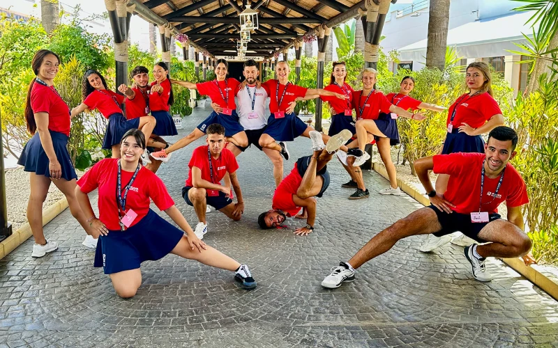 Grupo de voluntarios con camisetas rojas en patio tropical, posando juntos
