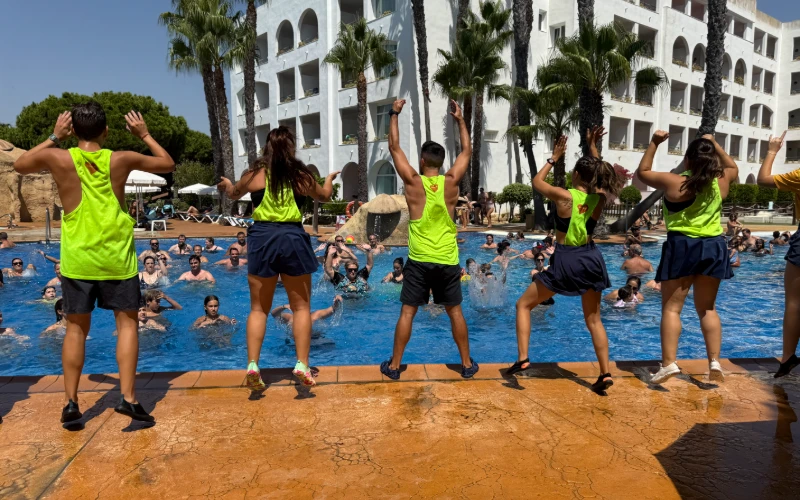 Ni&ntilde;os en piscina con camisetas verdes haciendo ejercicios frente al hotel
