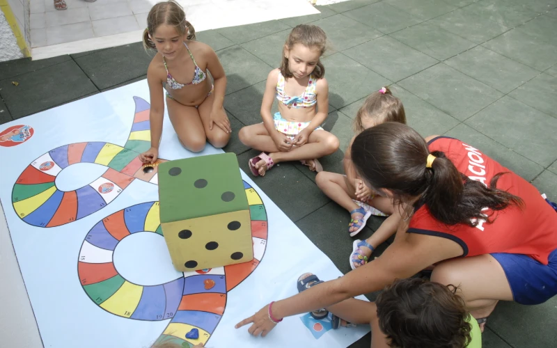 Ni&ntilde;as jugando con un dado gigante de colores en el suelo.