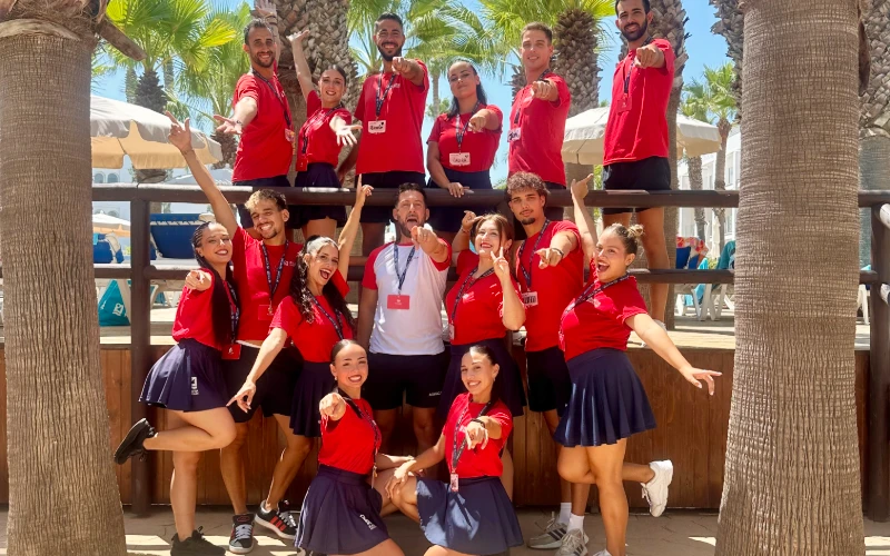 Grupo de personas con camisetas rojas posando en un entorno con palmeras