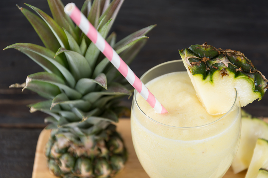 Cóctel de piña colada con pajita y un trozo de piña como decoración
