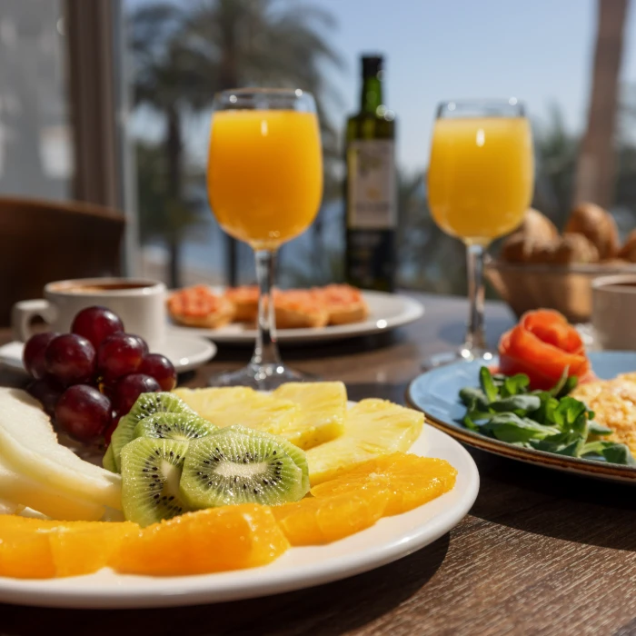 Desayuno con frutas y jugo de naranja sobre la mesa.