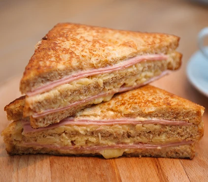 S&aacute;ndwich Monte Cristo cortado en tri&aacute;ngulos sobre una tabla de madera.