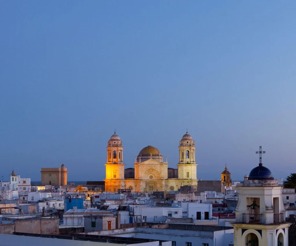 Panorama de una ciudad con c&uacute;pula dorada y dos torres sobre el atardecer