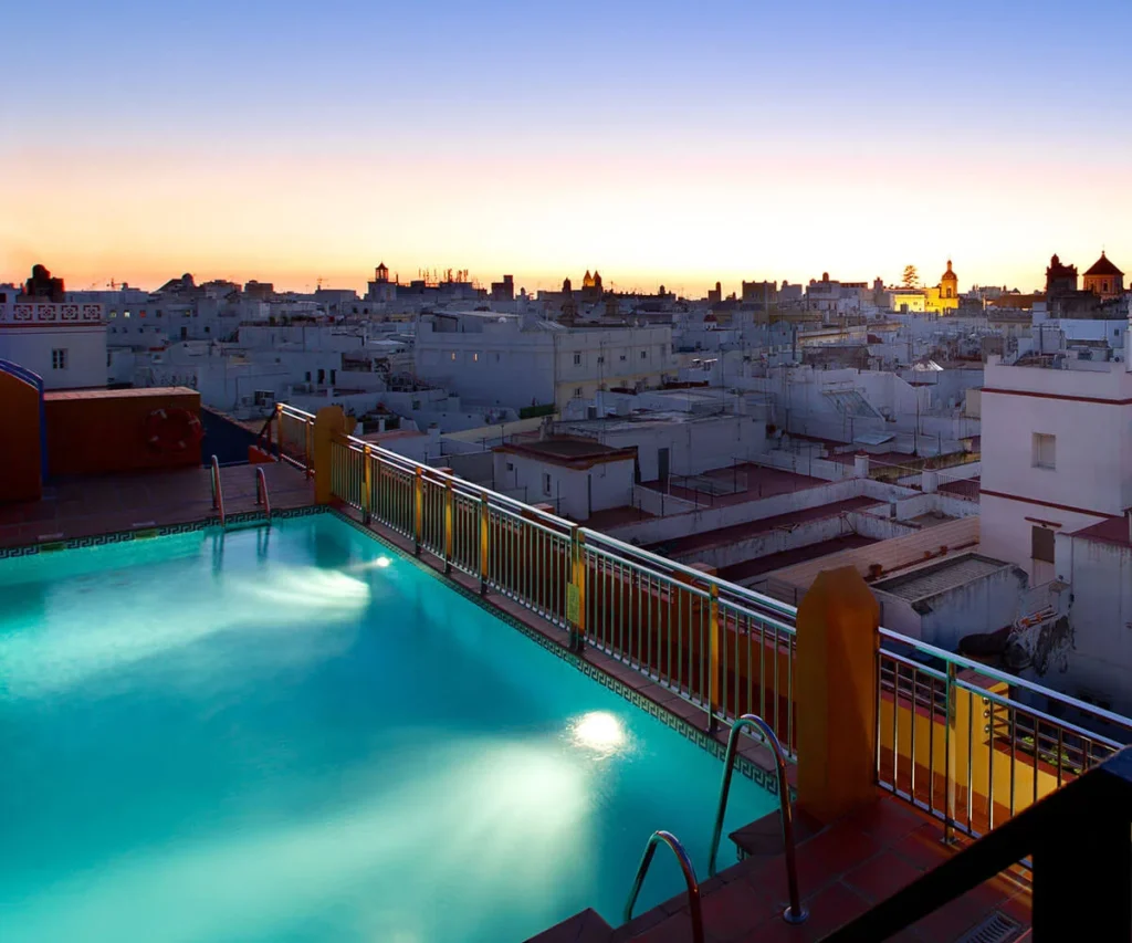Piscina con balc&oacute;n y vistas del casco urbano al atardecer