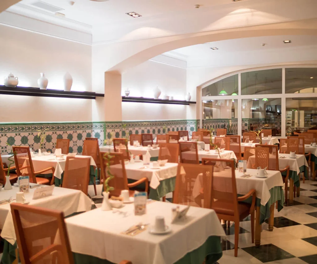Comedor de restaurante con mesas servidas, sillas de madera y decoraci&oacute;n tradicional
