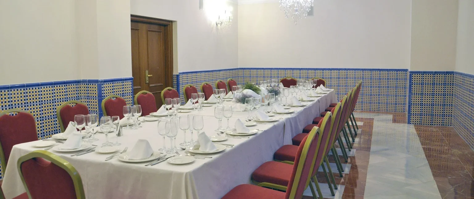 Mesa de banquete con copas y sillas en sala con mosaicos azules y blancas