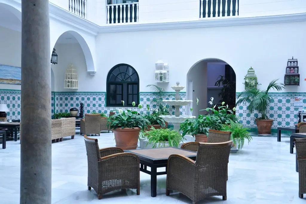 Patio blanco con arcos, mesas y plantas en macetas, estilo mediterr&aacute;neo