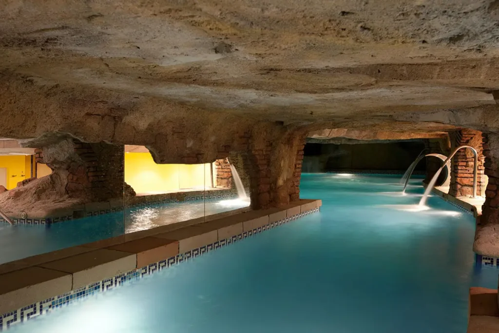 Piscina interior con chorros de agua y arcos de ladrillo en un spa subterr&aacute;neo
