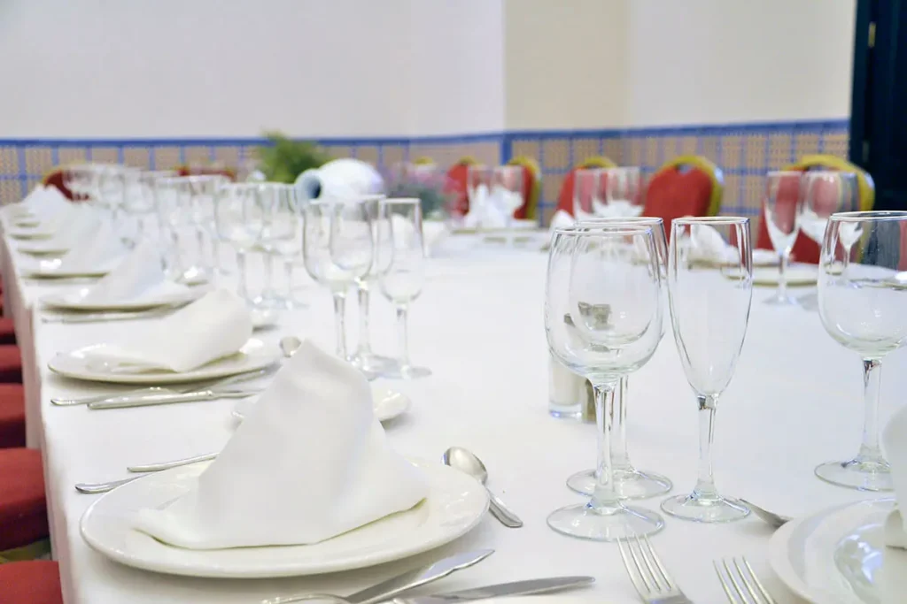 Mesa de banquete con copas y platos blancos en un evento al aire libre