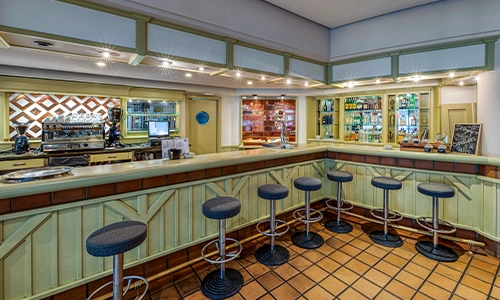 Bar luminoso con sillas altas y mostrador en esquina.
