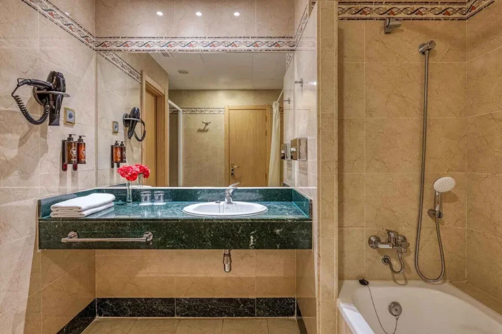 Ba&ntilde;o moderno con lavabo y ba&ntilde;era, ducha y grifer&iacute;a met&aacute;lica, azulejos beige