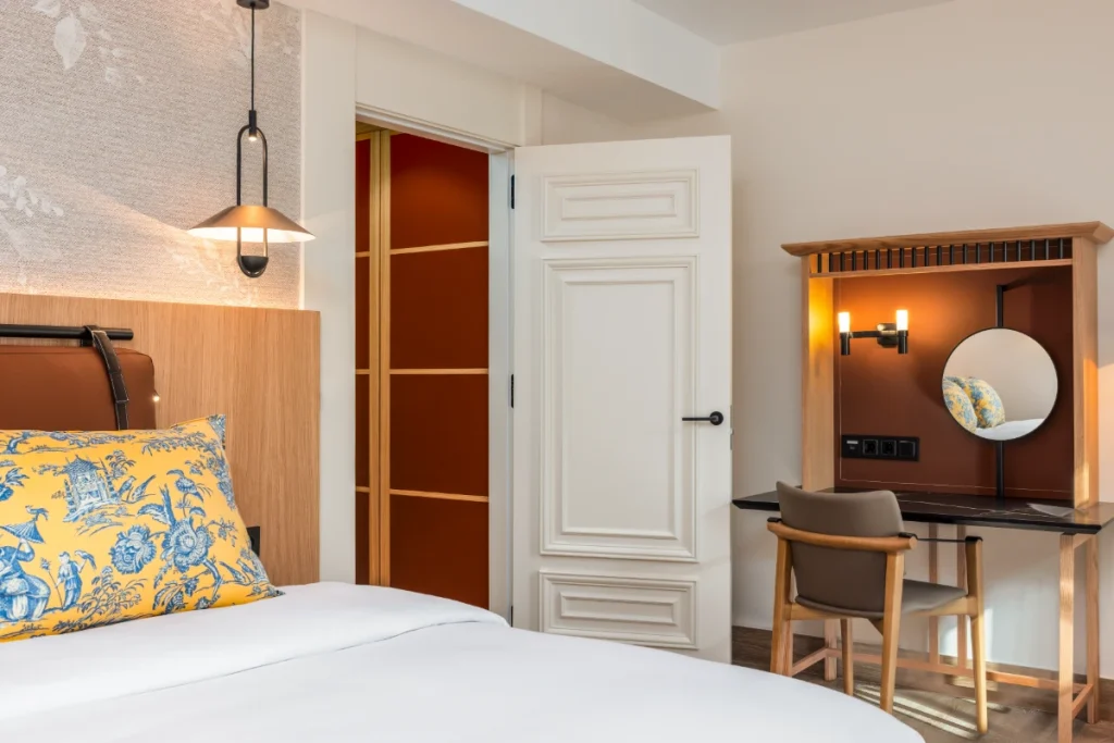 Dormitorio moderno con cama, l&aacute;mparas y escritorio de madera con espejo redondo