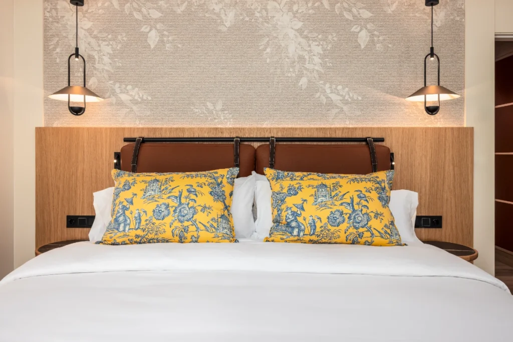 Cama doble con almohadas estampadas azules y cabecero de madera en suite.