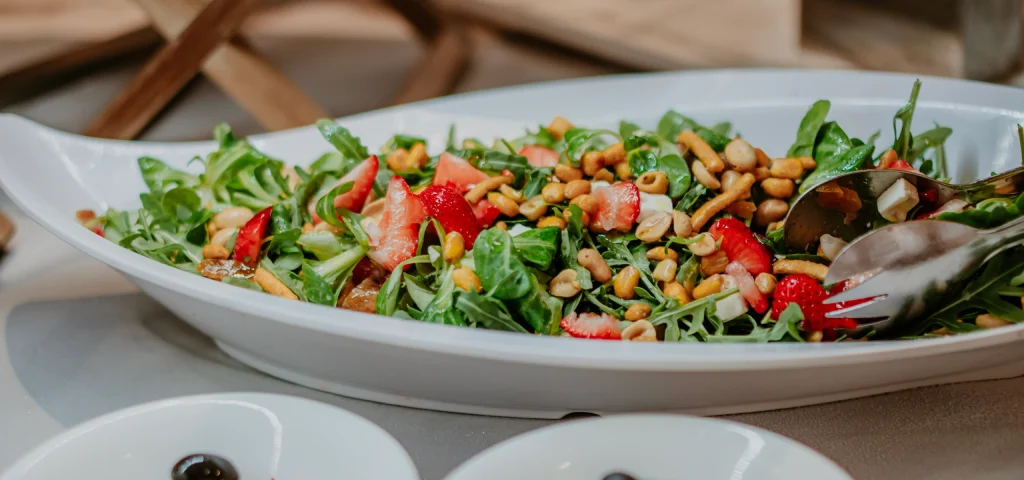Ensalada con fresas, queso y frutos secos en un plato blanco.