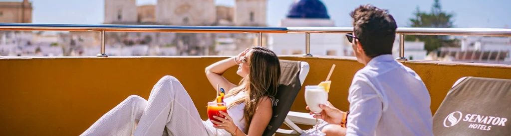 Pareja disfrutando c&oacute;cteles en la terraza de un hotel con vistas a la ciudad.