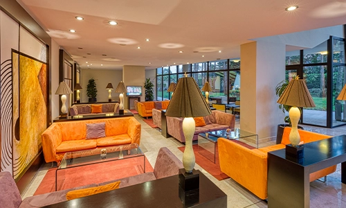 Sala moderna con sof&aacute;s naranjas y l&aacute;mparas, decorada con arte abstracto.