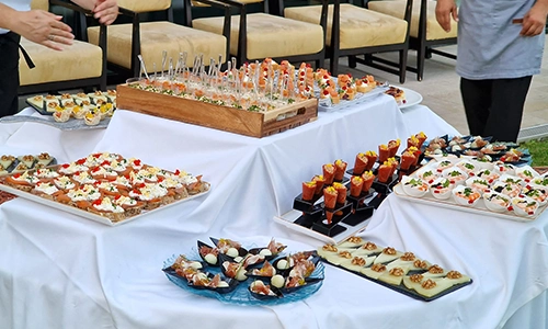 Mesa con variedad de aperitivos gourmet sobre mantel blanco.