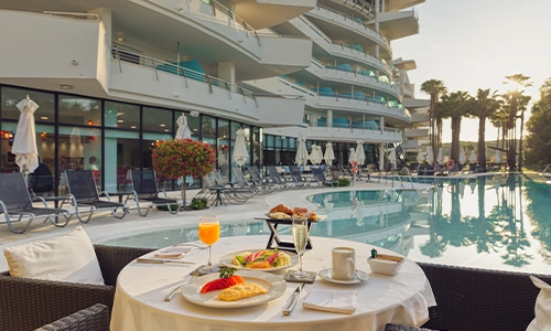 Desayuno junto a una piscina en un hotel moderno con cielos despejados.