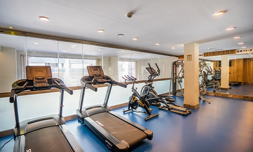 Gimnasio moderno con m&aacute;quinas de ejercicio y espejos en la pared.
