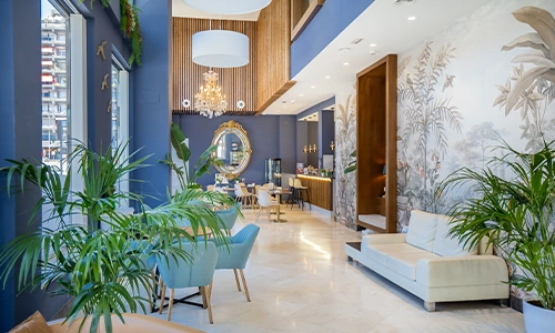 Sal&oacute;n elegante con decoraci&oacute;n azul, plantas, luz natural y candelabro.