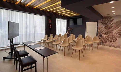 Sala de conferencias con sillas blancas y pantalla, iluminada y decorada.