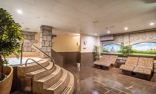 Spa con piscina, tumbonas de mosaico y decoraci&oacute;n pintada en paredes.