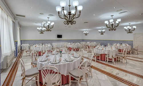 Sal&oacute;n de banquetes elegante con mesas redondas y candelabros.