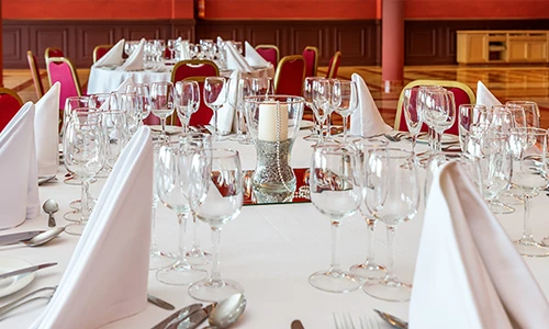 Mesa de banquete elegante con copas, velas y servilletas blancas.