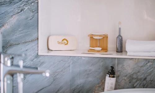 Estante de ba&ntilde;o con jab&oacute;n, toalla y botella decorativa.