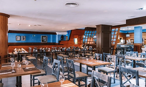 Restaurante amplio y elegante con mesas vac&iacute;as y decoraci&oacute;n de madera.