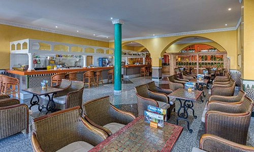 Cafeter&iacute;a con muebles de mimbre y barra de servicio en un ambiente amplio.