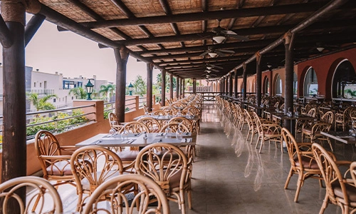 Terraza de restaurante con sillas y mesas vac&iacute;as al aire libre.