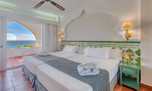 Habitaci&oacute;n luminosa con dos camas y balc&oacute;n con vista al mar.