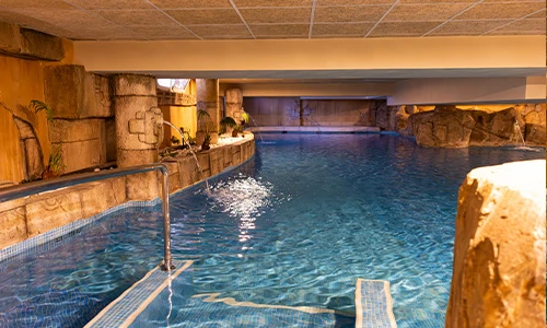 Piscina cubierta con paredes estilo piedra y barandillas met&aacute;licas.