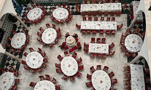Vista a&eacute;rea de mesas redondas y rectangulares con manteles blancos y sillas rojas.