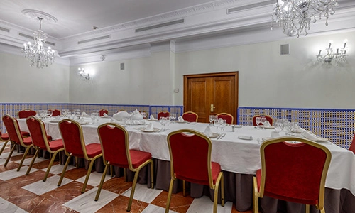 Sala de banquete con mesas dispuestas en U y sillas rojas alrededor.
