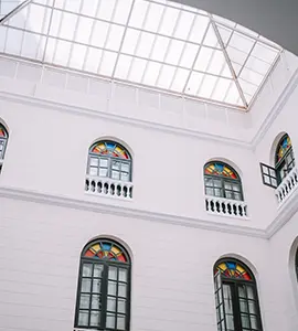 Fachada blanca con arcos y ventanas altas y abovedadas, techo de vidrio