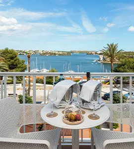 Mesa con sombrilla y vista al mar y costa desde un balc&oacute;n.