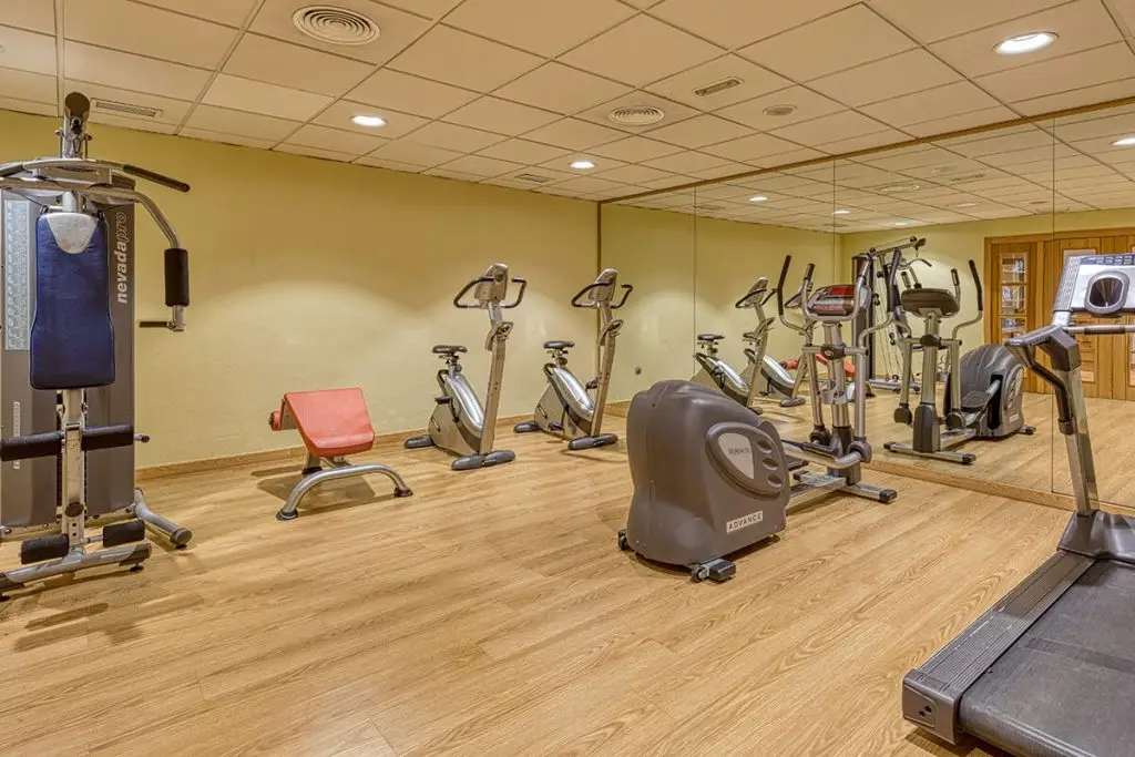 Sala de gimnasio con máquinas de ejercicio y equipo cardiovascular en fila