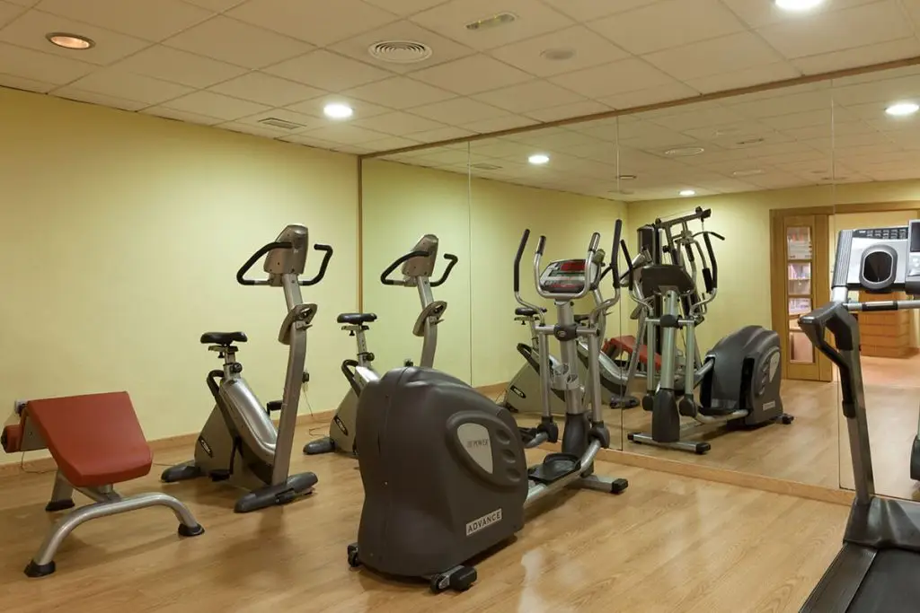 Gimnasio con bicicletas y máquinas de ejercicio en un cuarto con espejos