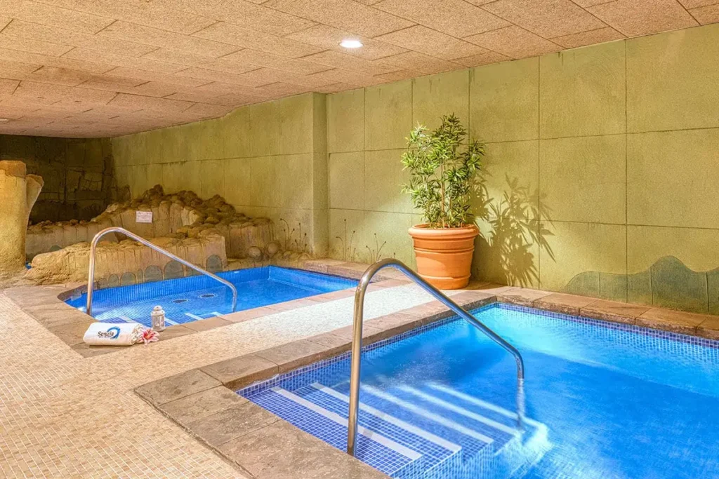 Piscinas interiores azules con escalera y plantas en maceta, en un spa.