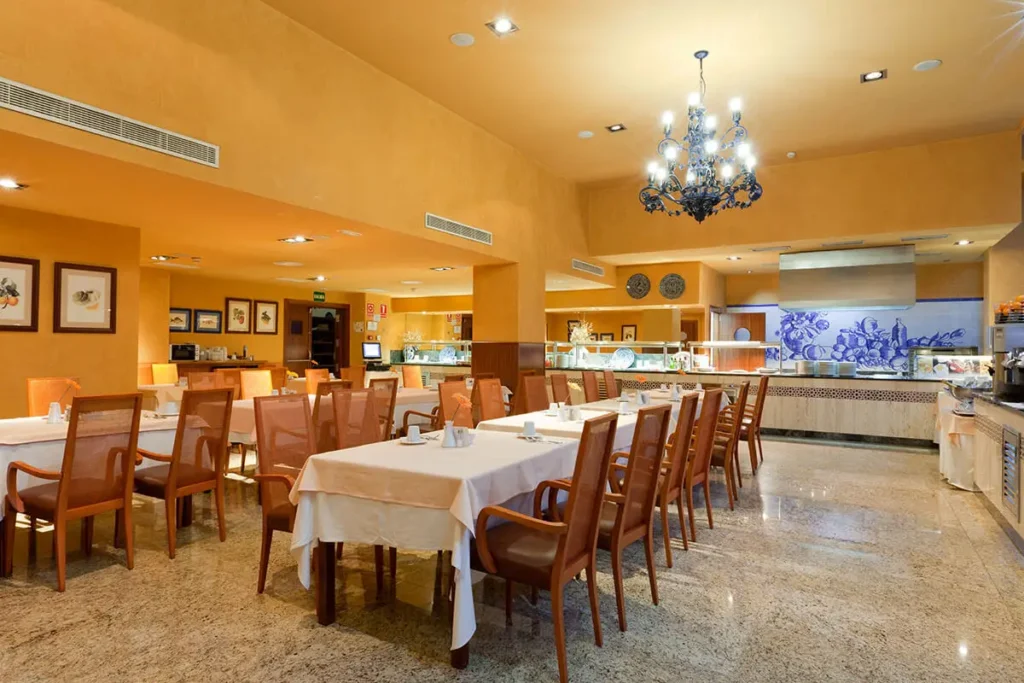 Sala de comedor de hotel con mesas, sillas y l&aacute;mpara de ara&ntilde;a azul