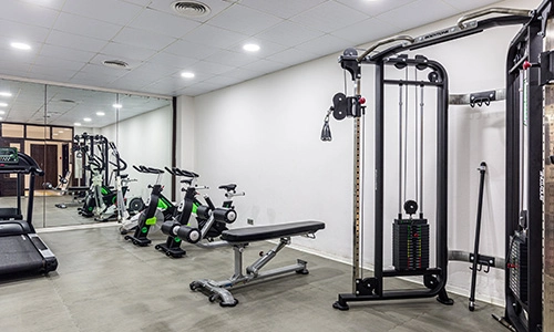 Gimnasio con equipo de entrenamiento y espejos en la pared.