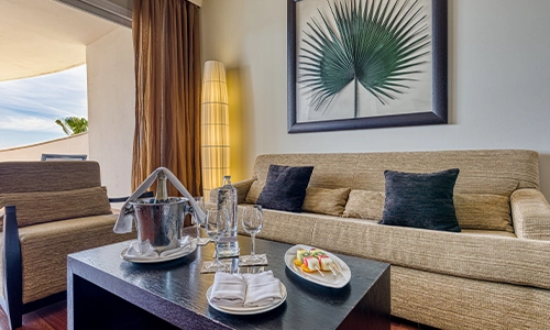 Sala elegante con sof&aacute;, mesa, y servicio de cortes&iacute;a. Decoraci&oacute;n moderna.