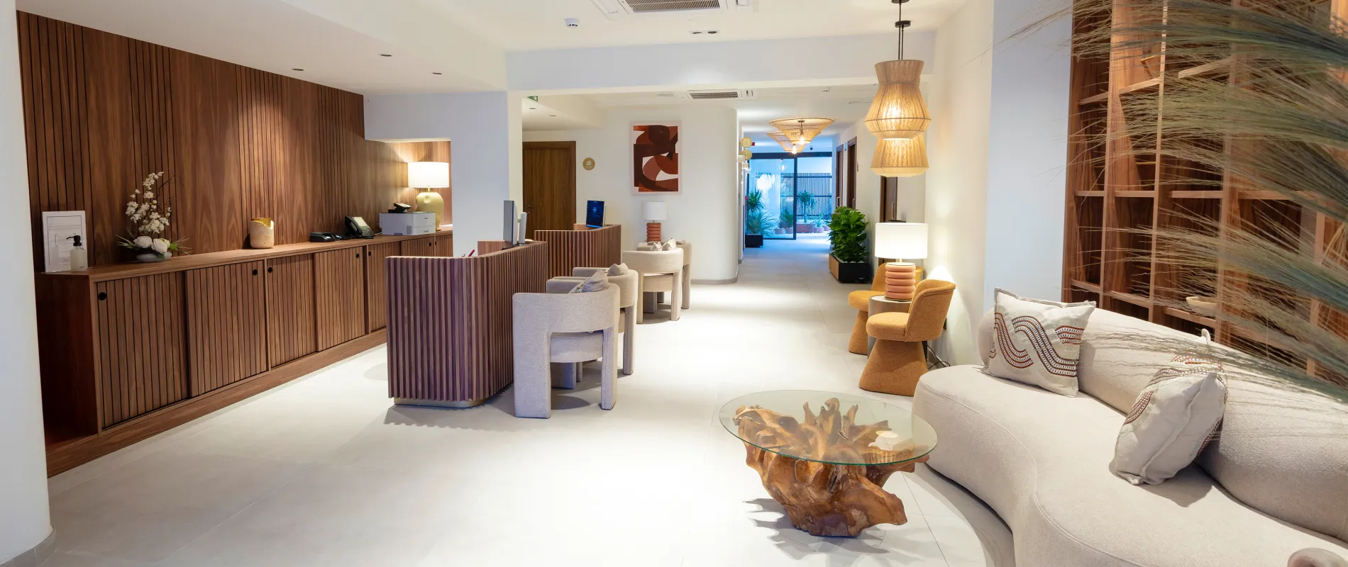 Lobby moderno con recepci&oacute;n, sof&aacute;s y mesa de vidrio, iluminaci&oacute;n c&aacute;lida.