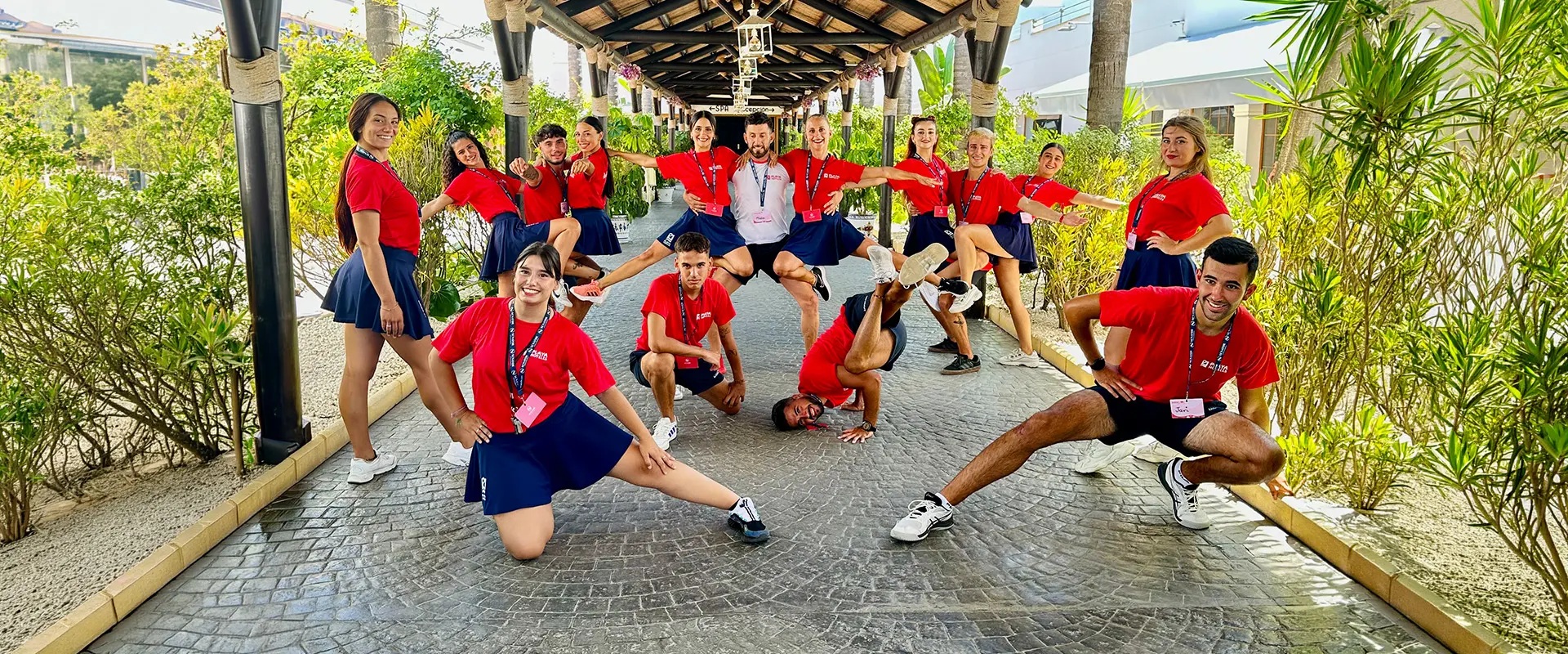 Equipo con camisetas rojas y azules posando en patio con plantas y soportales