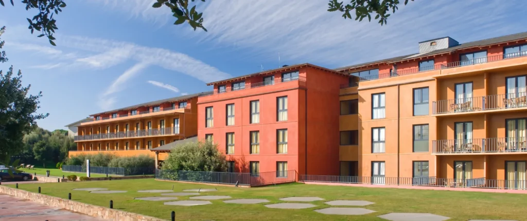Complejo hotelero de varios pisos con balcones y jard&iacute;n bajo cielo despejado
